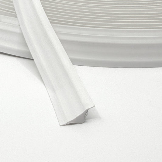 White Smart Edge trim coiled on a flat surface with adhesive backing visible.