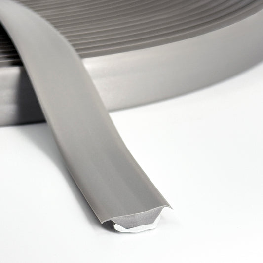 Close-up of gray Smarter Trim roll with adhesive backing partially exposed.