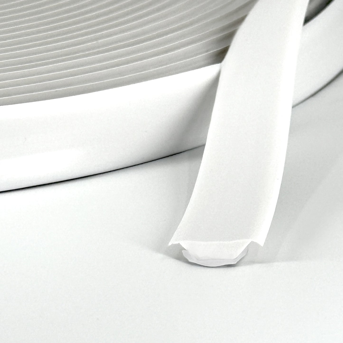 Close-up of white Smarter Trim roll with adhesive backing partially exposed.