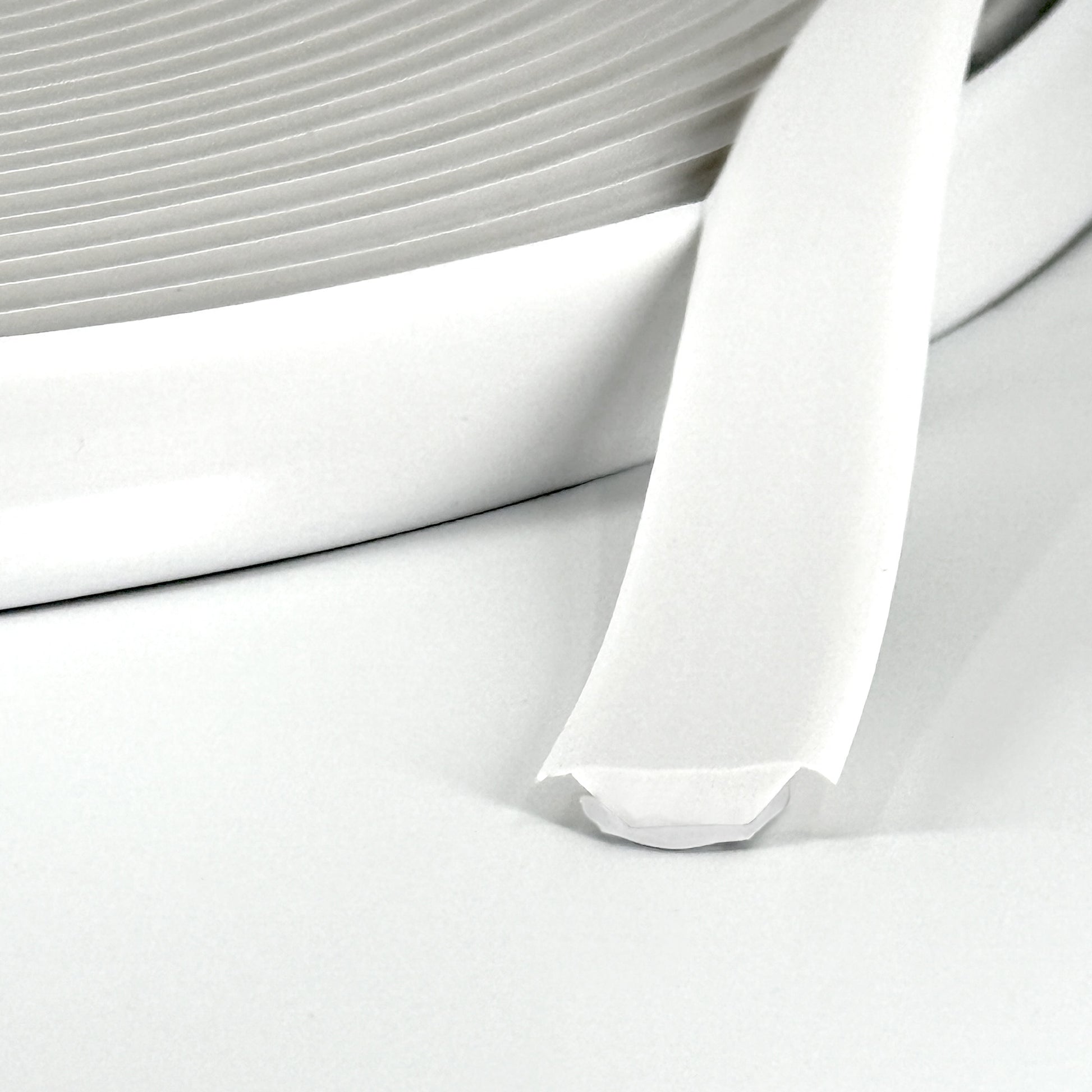 Close-up of white Smarter Trim roll with adhesive backing partially exposed.
